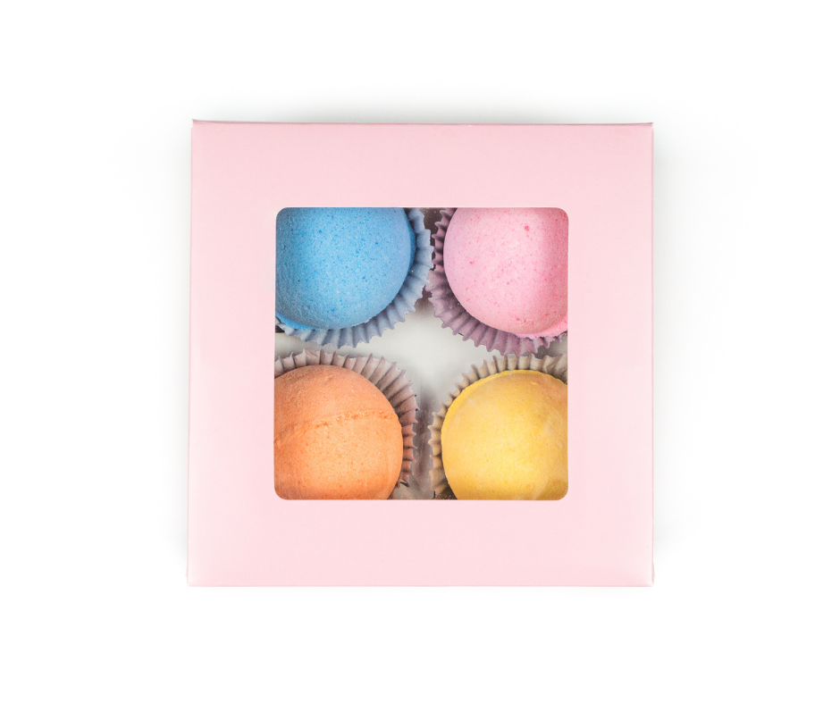 Pink box with colorful bath bombs inside on a white background