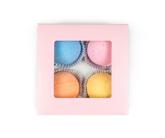 Pink box with colorful bath bombs inside on a white background